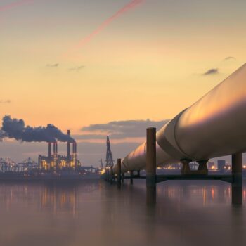 Oil pipeline in industrial district with factories at dusk
