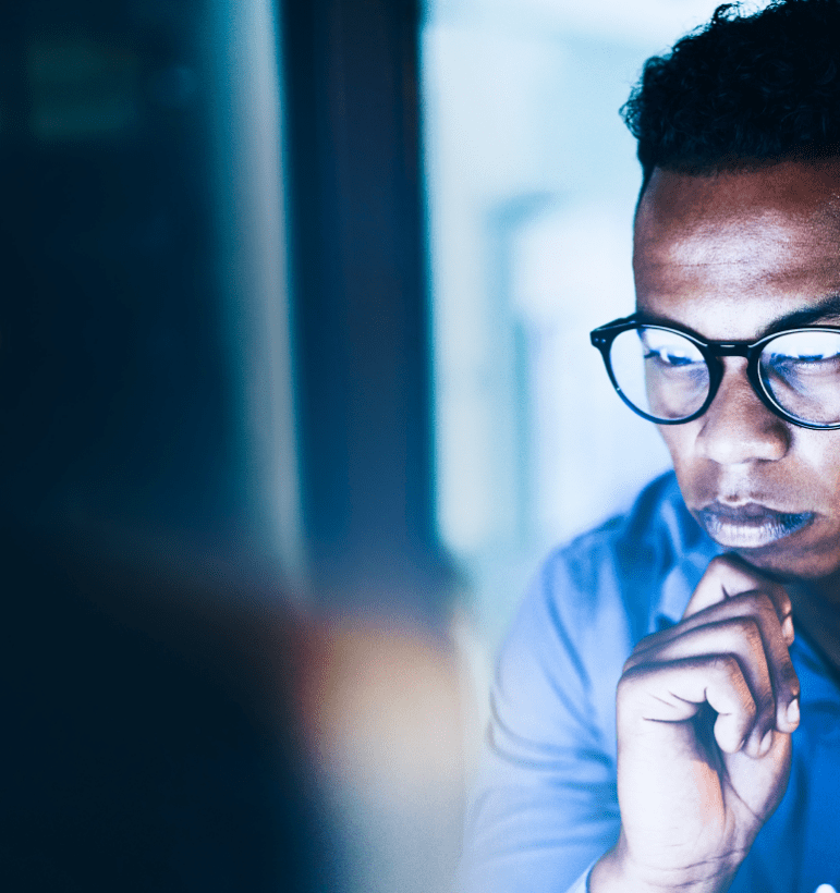 Man wearing glasses staring at computer screen